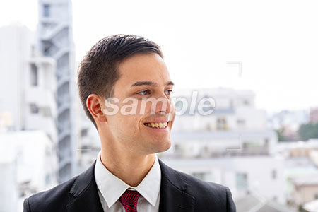 オフィス街でビジネスマンが右を見て微笑む a0010029PH