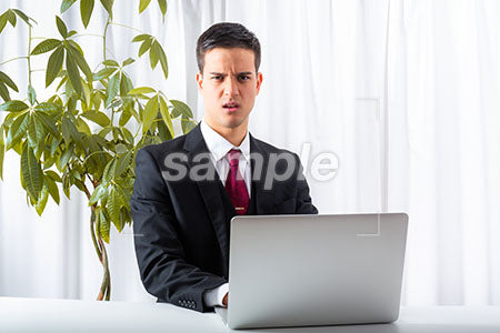 パソコンデスクの前で男性が正面を見て怒る a0010176PH