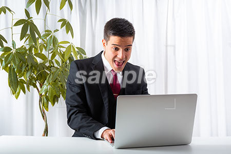 仕事をしながらパソコンを見て驚く男性 a0010227PH