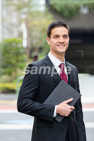 都会で仕事をしている男性が右を見て微笑む a0010362PH