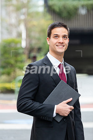 オフィス街でビジネスマンが斜め上を見上げて微笑む a0010363PH