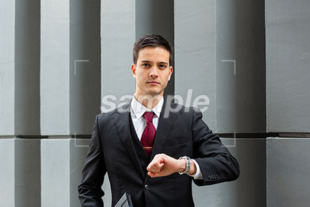 時間をきにして腕時計を出しているビジネスマンの男の人が正面を見る a0010492PH