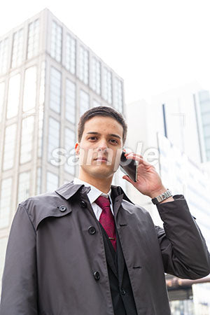 コートを着たビジネスマンが電話しながら正面を見る a0010547PH