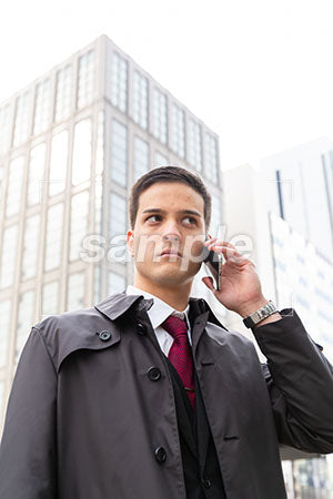 オフィス街でスマホで電話しながら右をチラッと見るビジネスマン a0010550PH