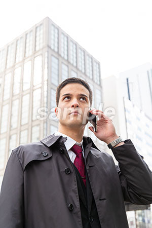 コートを着た外国人男性が電話しながら右上を見る a0010552PH