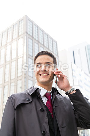 コートを着たビジネスマンが電話しながら笑っている a0010555PH