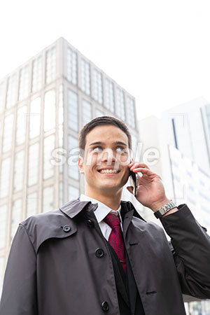 コートを着た男性が電話しながら右上を見て笑う a0010558PH