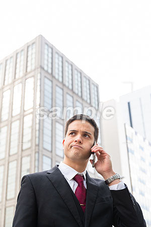 ビル街で電話しながら悩む表情の男性 a0010590PH