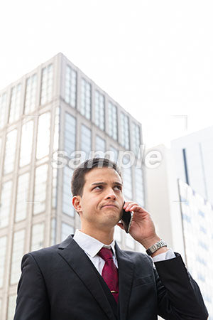 オフィス街で電話しながら右上を見て考えるビジネスマン a0010592PH