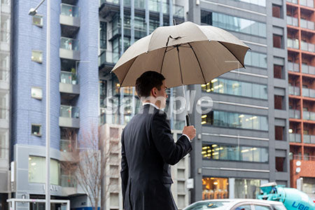 ビジネスマンが傘をさして歩く a0010597PH