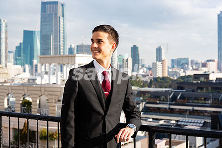 東京のビル街と外国のビジネスマンが左を見て微笑む a0010618PH