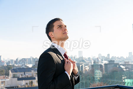 屋上でネクタイを触りながら右上を見る男性の横顔 a0010706PH