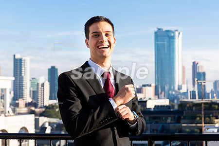 高層ビルと正面を見て笑う黒いスーツの男性 a0010743PH