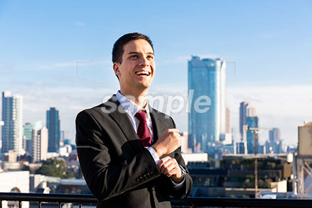 高層ビルの屋上で右上を見て笑う男性 a0010746PH
