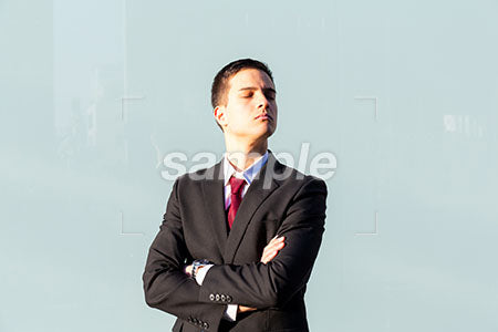 外でビジネスマンが腕を組んで目を閉じる、水色の背景 a0010850PH