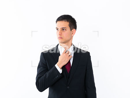 外国のビジネスマンがネクタイを直しつつ左を見る a0010995PH