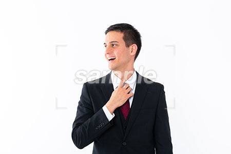 スーツを着ている外国人男性が左を見て笑う a0011008PH