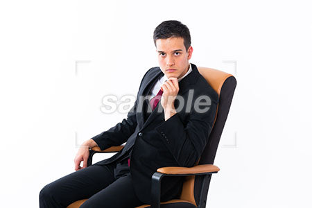 深く椅子に座っている男がアゴに手をあてて正面を見る a0011155PH