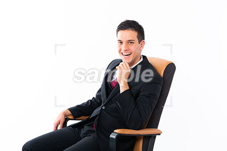 椅子に座っているビジネスマンの男性、顎に手を添えて笑う a0011164PH