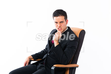 デスクの椅子に腰掛けて、顎に手を添えて怒る男性 a0011171PH