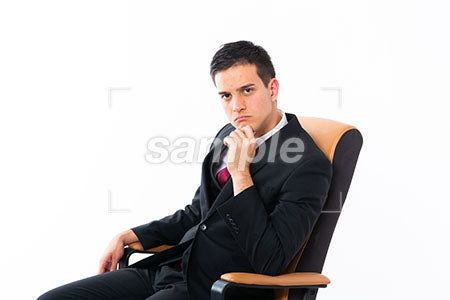 座った男性がアゴに手を添えて正面を見る a0011181PH