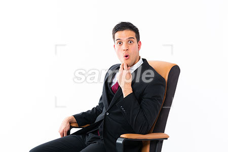 椅子に座ってビジネスマンの男性の驚嘆！の表情　顎に手を添えて正面を見て驚く a0011195PH