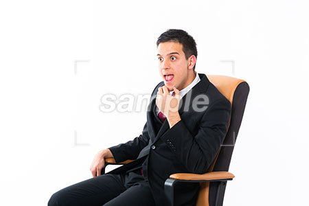 椅子にゆったり座った男性が顎に手を添えて左を見て変な顔 a0011197PH