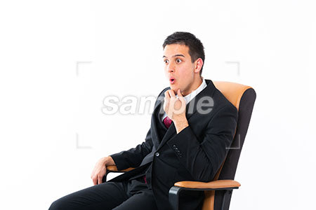 椅子に座ってビジネスマンの男性の驚嘆！の表情　顎に手を添えて左を見て驚く a0011198PH