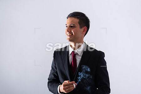 タバコを持って左を見て笑う黒いスーツの男性 a0011293PH