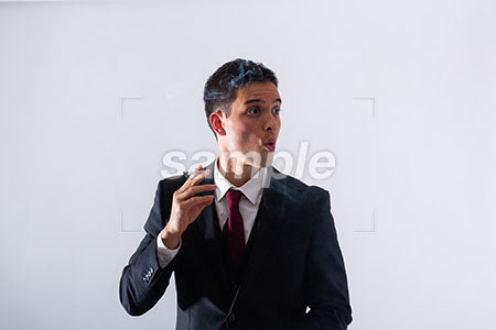 スーツの男性が煙草をふかして右を見て驚く a0011306PH
