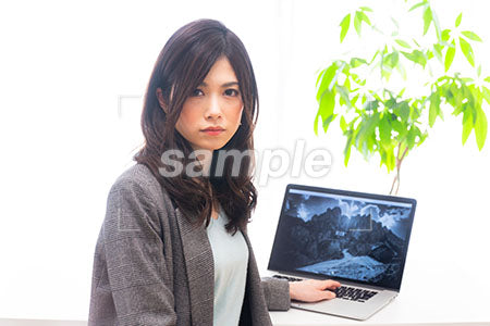 パソコンの前で正面を見つめる女の人 a0020014PH
