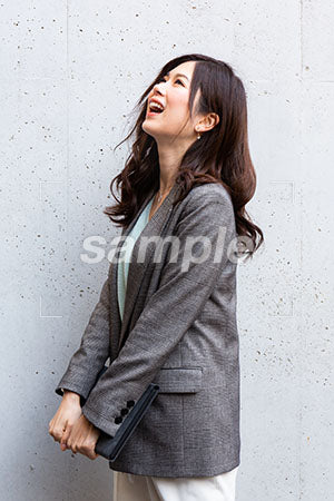 ジャケットを着た女性が両手でPCを持って笑っている a0020135PH