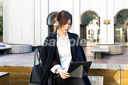 公園で仕事をしている女性が膝にパソコンを乗せる a0020495PH