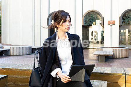 外出して仕事をしている女性の膝にパソコンを乗せる a0020496PH