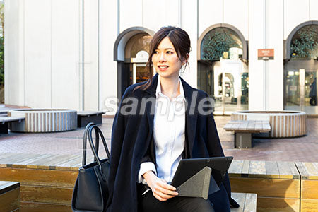 外出して仕事をしている女性の左を見て微笑む a0020499PH