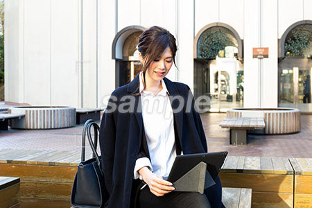 屋外で仕事をしている女性のパソコンを見て微笑む a0020500PH