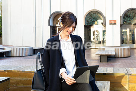 外で仕事をしている女性のパソコンを見て笑う a0020503PH