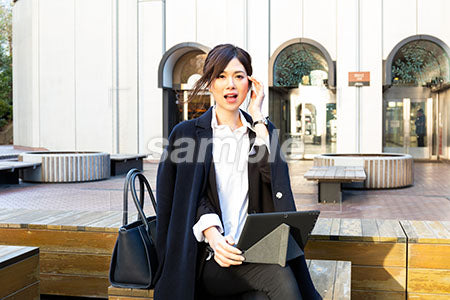 屋外の広場でコートを着た女性が顔に手をあててちょっと驚く a0020522PH