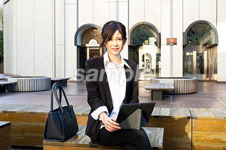 昼休みに屋外に出て仕事をしている女性が正面を見て微笑む a0020534PH