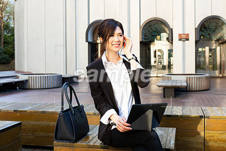 昼休みに外で仕事をしている女性が耳に手を添えて微笑む a0020536PH