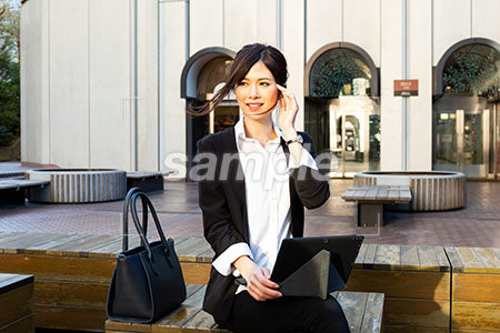 昼休みに外で仕事をしている女性が顔に手を添えて微笑む a0020537PH