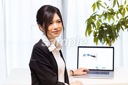 業務中にパソコンの前で微笑むスーツの女性 a0020607PH
