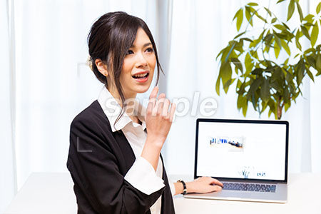 パソコンの前で笑顔ではなすスーツの女性 a0020632PH