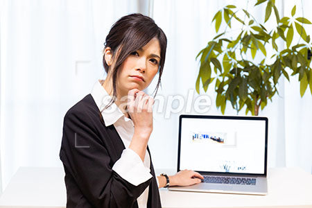 パソコンの前で悩むスーツの女性 a0020634PH