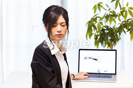 パソコンの前で目をつぶるスーツの女性 a0020638PH