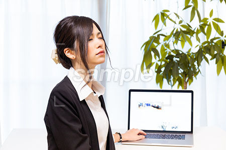 パソコンデスクの前で目を閉じる女性 a0020640PH