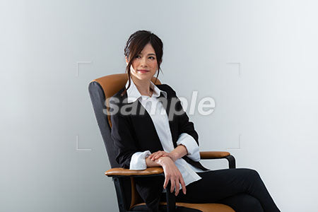 椅子にゆったりと腰掛けた女性が、左上を見て微笑む a0020958PH
