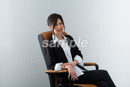 椅子にゆったりと腰掛けた女性が右上を見て微笑む a0020960PH