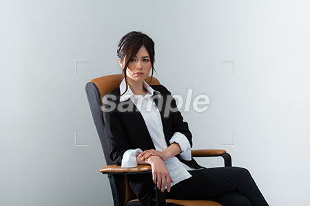スーツの女性が椅子に座って左下を見る、怒る a0020967PH