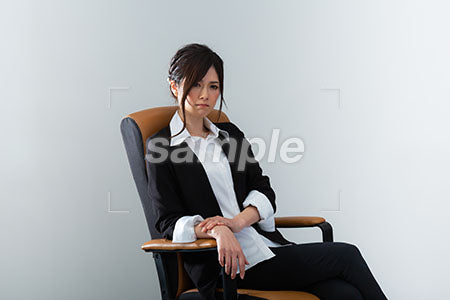 スーツの女性がイスに座って右下を見る a0020968PH